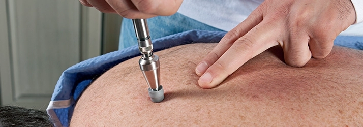 Chiropractor using the Activator Method on a patients back.