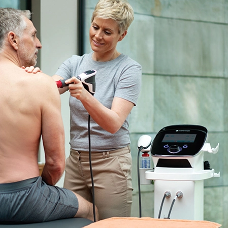 Person receiving radial pressure wave therapy on their shoulder.