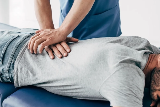 Chiropractor adjusting a mans lower back.